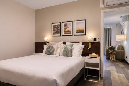 Chambre confortable avec lit double, linge blanc, tables de chevet éclairées et décor mural aux Appartements Husseren Collections 4 étoiles