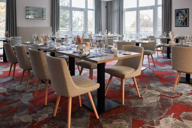 Elegantes Restaurant mit gedeckten Tischen und bequemen Sesseln, kulinarisches Erlebnis in der Nähe von Colmar im Elsass