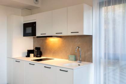 Cuisine équipée d’un appart-hôtel avec plan de travail, évier, électroménager intégré et éclairage sous meubles près de Colmar, en Alsace