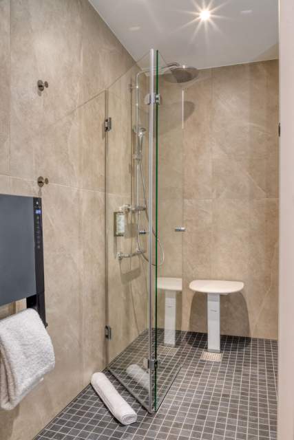 Badezimmer eines Aparthotels mit ebenerdiger Dusche, Glaswand und Hocker in der Nähe von Colmar im Elsass
