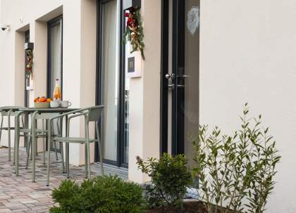 Entrée d’un appart-hôtel avec terrasse, table extérieure et accès privatif aux logements près de Colmar, en Alsace