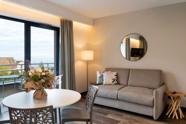Aufenthalt in einem Aparthotel mit Sofa, Essecke, Wandspiegel und Zugang zur Terrasse in der Nähe von Colmar im Elsass, in den Appartements Husseren Collections