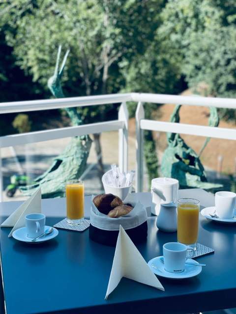 Frühstück auf der Terrasse eines Aparthotels mit heißen Getränken, Fruchtsäften und Gebäck in der Nähe von Colmar im Elsass