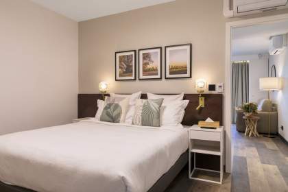 Chambre d’un appart-hôtel avec lit double, décoration soignée, tables de chevet éclairées et accès à la salle de bain près de Colmar, en Alsace