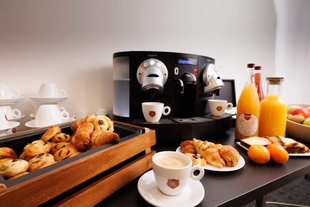Frühstücksbereich eines Aparthotels mit Kaffeemaschine, Gebäck, Fruchtsäften und Tassen in der Nähe von Colmar im Elsass