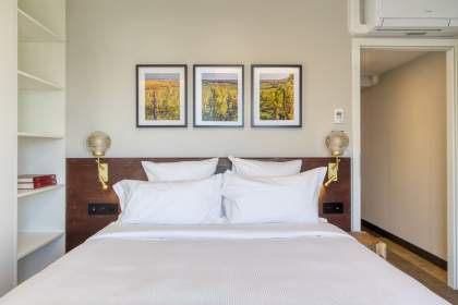 Chambre appartements hôtel avec lit double, matelas confortable, draps blanc, décoration murale, accès à un balcon avec vue sur la plaine près d'Alsace