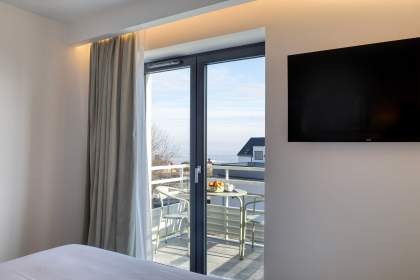 Chambre d’un appart-hôtel avec baie vitrée donnant sur un balcon et vue extérieure près de Colmar, en Alsace