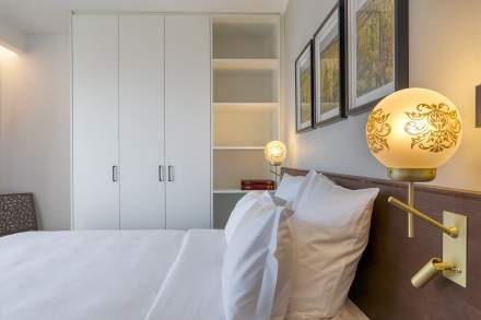 Chambre d’un appart-hôtel avec lit double, rangements intégrés et éclairage chaleureux près de Colmar, en Alsace, aux Appartements Husseren Collections