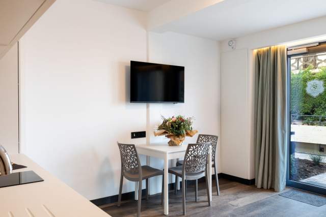 Essbereich eines Aparthotels mit Tisch, Designerstühlen und Wandfernseher in der Nähe von Colmar im Elsass, in den Appartements Husseren Collections