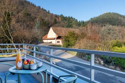 Balcon d’un appart-hôtel avec table, chaises et vue sur la nature et les collines alsaciennes près de Colmar, en Alsace