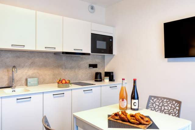 Ausgestattete Küche und Essbereich eines Aparthotels mit eingebauten Elektrogeräten und Willkommensprodukten in der Nähe von Colmar im Elsass