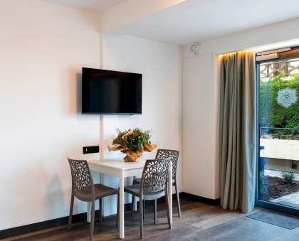 Coin repas d’un appart-hôtel avec table, chaises design et télévision murale près de Colmar, en Alsace