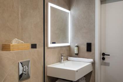 Salle de bain avec vasque moderne, miroir lumineux et rangements intégrés dans nos appartements près de Colmar, en Alsace