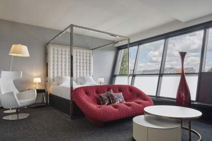 Hotelzimmer Athena Spa, großes Bett, Wohnbereich mit Sofa und Couchtisch, großes Fenster. <br />
 