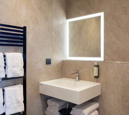 Salle de bain d’un appart-hôtel avec vasque et robinetterie moderne, séche-serviettes 