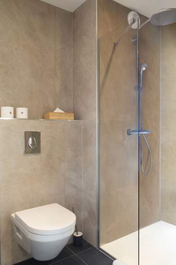 Salle de bain moderne d’un appart-hôtel avec douche à l’italienne, WC suspendu, sèche-serviettes et finitions contemporaines près de Colmar, en Alsace