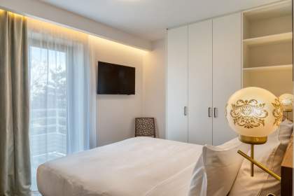 Chambre d’un appart-hôtel avec lit double, rangements intégrés, télévision murale et accès au balcon près de Colmar, en Alsace