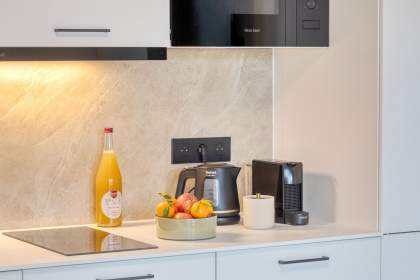 Plan de travail d’une cuisine d’appart-hôtel avec machine à café, bouilloire, fruits et produits locaux en Alsace