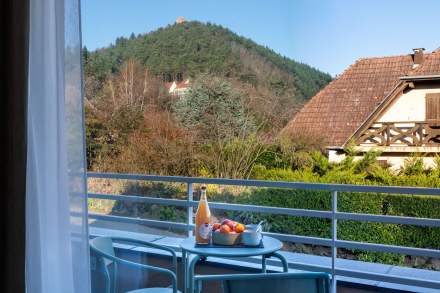 Balcon d’un appart-hôtel avec table, chaises et petit-déjeuner face aux collines alsaciennes près de Colmar, en Alsace