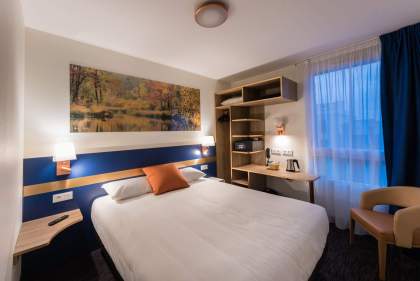 Hotelzimmer K, großes Bett, Bürobereich, großes Fenster mit Blick nach draußen. <br />
 