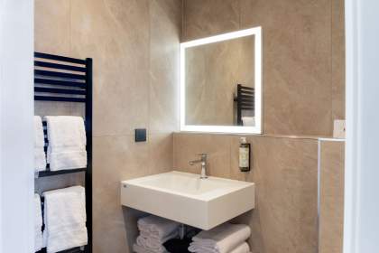 Salle de bain d’un appart-hôtel avec vasque moderne, miroir lumineux, sèche-serviettes et finitions contemporaines près de Colmar, en Alsace