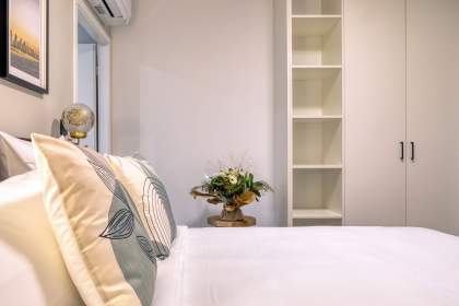 Chambre d’une résidence avec lit double, coussins décoratifs, étagères de rangement, bouquet de fleures proche d'Eguisheim