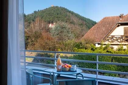 Balcon d’un appart-hôtel avec table, chaises et petit-déjeuner face aux collines alsaciennes près de Colmar, en Alsace