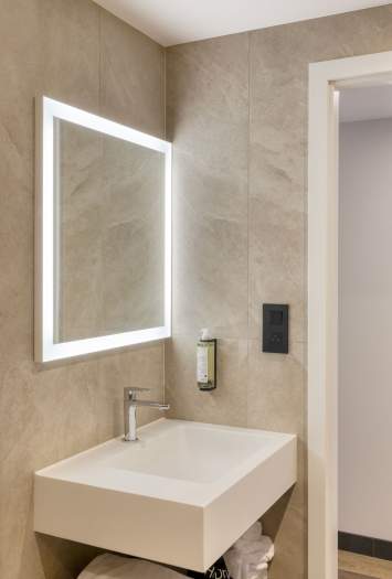 Salle de bain de l’appartement, vasque moderne et miroir lumineux près de Colmar, en Alsace