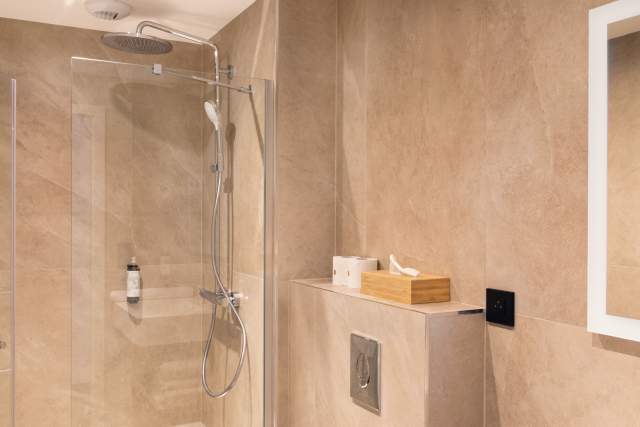 Modernes Badezimmer eines Aparthotels mit ebenerdiger Dusche, modernen Armaturen und integrierten Stauräumen in der Nähe von Colmar im Elsass