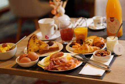 Breakfast tray served with pastries, bread, cold cuts, hot drinks, and fruit juices in a serviced apartment near Colmar, Alsace